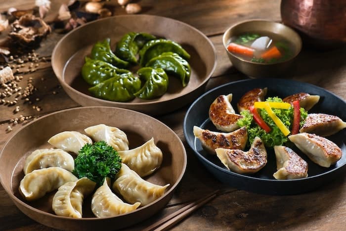 Assorted Asian dumplings on wooden table.