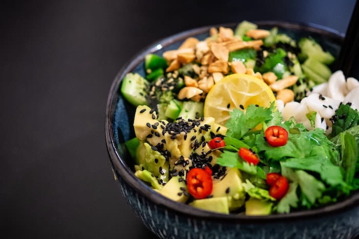 Colorful avocado salad in a dark bowl.